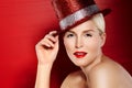 She was born for Hollywood. Portrait of a beautiful showgirl with red lipstick and a sparkly red hat against a red