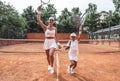 That was a great game! Full length shot of a woman tennis trainer and sporty girl child on court. Tennis coach and little player Royalty Free Stock Photo