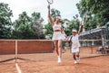 That was a great game! Full length shot of a woman tennis trainer and sporty girl child on court. Tennis coach and little player Royalty Free Stock Photo