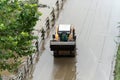 Due to the flood, mud piled up on the riverside bike paths is being cleaned up with skid loader Royalty Free Stock Photo