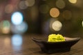 Wasabi in black saucer on wooden table with depth of field effect, Japanese food`s condiment, bokeh background