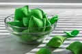 Wasabi-style corn chips in the form of pillows lie in a glass bowl on a white background, sanctified by the sun`s rays passing