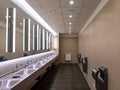 Wash-basins and hand dryers in a modern restroom with large mirrors Royalty Free Stock Photo