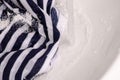 Wash a stain on white clothes under water stain powder for washing Royalty Free Stock Photo