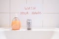 Wash your hands handwritten notice above bathroom sink