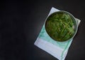 Washed green leaves of fresh sorrel are placed on a metal mesh to dry on a napkin on a dark concrete background.