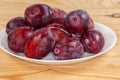 Washed plums on dish on rustic table, side view closeup Royalty Free Stock Photo