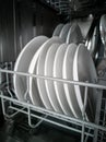 Washed porcelain white plates in the dishwasher. Cleaning and cleanliness concept