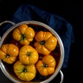 Washed various tomatoes in a colander on a black background