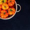 Washed various tomatoes in a colander on a black background