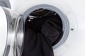 Washing black clothes, open wash machine closeup