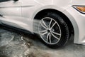 Washing a car by hand, car detailing. Close up image of the process of cleaning the car wheels with a water gun. Car