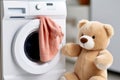 Washing children's clothes. Washing machine with a clean washed towel and a teddy bear in the laundry room