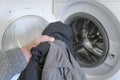 washing dark clothes. man's hand folds clothes into an open washing machine