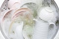 Washing dishes, utensils soaking in kitchen sink Royalty Free Stock Photo