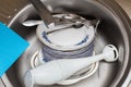 Washing dishes. Forks, spoons, plates of different sizes, rags in the sink under running water. Royalty Free Stock Photo