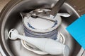 Washing dishes. Forks, spoons, plates of different sizes, rags in the sink under running water Royalty Free Stock Photo