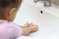 Washing hands with soap under the faucet with water. Little girl washing hands with water and soap in bathroom.Hygiene