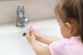 Washing hands with soap under the faucet with water. Little girl washing hands with water and soap in bathroom.Hygiene