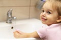 Washing hands with soap under the faucet with water. Little girl washing hands with water and soap in bathroom.Hygiene