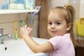 Washing hands with soap under the faucet with water. Little girl washing hands with water and soap in bathroom.Hygiene