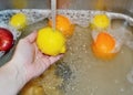 Washing lemon and other fruits under tap water in sink