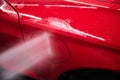 Washing a modern red car at a car wash using a pressure washer Royalty Free Stock Photo