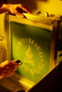 Washing out the emulsion from a screen printing screen in a darkroom under amber safelights for t-shirt printing