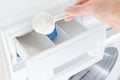 Washing powder, detergent in a cup and womans hand, washing machine, selective focus
