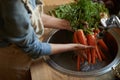 Washing them off before its time to cook. a woman washing carrots in a sink.