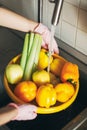 Washing vegetables. Hands in pink gloves washing vegetables in yellow bowl under water stream in sink. Woman  cleaning fresh Royalty Free Stock Photo