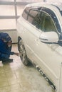 Washing a white car. Man worker washing windshield with sponge on a car wash. Manual car wash in car wash shop service. toned.