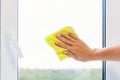 Washing a window pane with a yellow microfiber cloth, close-up with a blurred background Royalty Free Stock Photo