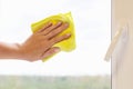 Washing a window pane with a yellow microfiber cloth, close-up with a blurred background. Royalty Free Stock Photo