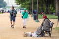 Washington DC, USA - June 9, 2019: Visitors to DC go for a stroll along the national mall. A homeless person sits on the bench at Royalty Free Stock Photo