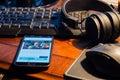 The Washington Post website on smartphone screen. Keyboard, headphones and mouse on wooden table. Working remotely from home