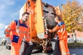 Waste collector gripping handle of garbage truck Royalty Free Stock Photo