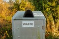 Waste sign on a silver steel trash can or bin in the countryside park Royalty Free Stock Photo