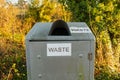 Waste sign on a silver steel trash can or bin in the countryside park Royalty Free Stock Photo