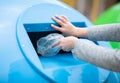 Waste Sorting. Female hand throwing plastic bag into blue recycle bin outdoors Royalty Free Stock Photo