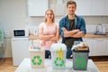 Waste sorting at home. Protect the environment. Young happy family put waste in colorful garbage bins with green Royalty Free Stock Photo