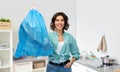 Smiling woman holding plastic trash bag with waste