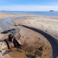 Waste water pipe with valve at sand beach at low tide Royalty Free Stock Photo