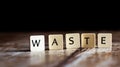 Waste word made of tiles on dark wooden background Royalty Free Stock Photo