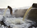 Wastewater from two large rusty pipes merge into the river