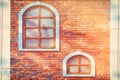 Wasting away the background of vintage brick walls. Texture of worn and dirty red brickwork and wooden windows. Background of the