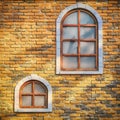Wasting away orange vintage brick walls. Background of brick wall is yellow with two windows. Texture of the old stained brickwork Royalty Free Stock Photo