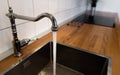 Water flowing out of a kitchen stainless steel tap into the sink. Water misuse in domestic duties and activities. Overusing
