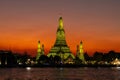 Wat Arun (Temple of the dawn) in Bangkok at dusk. Bathed in yellow light. Orange sky in background. Royalty Free Stock Photo