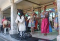 A young thai woman praying at buddah temple with Corona mask. In the background: dance and music group in traditional clothes